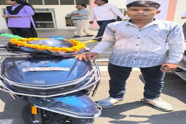 फूलों से सजी नीले रंग की स्कूटी के पास खड़ा एक छात्र