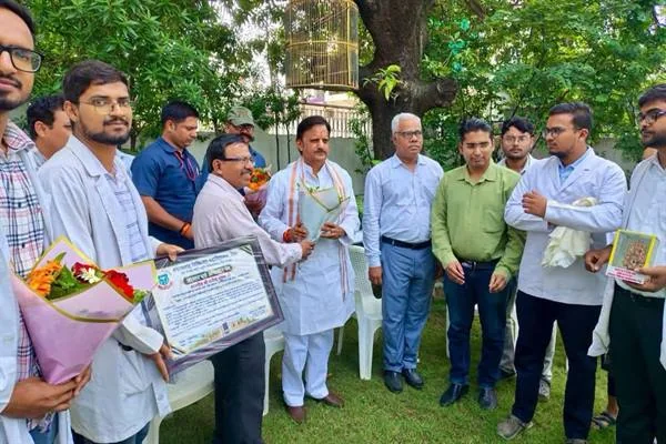 पेड़ों के बीच खुले परिसर में उप मुख्यमंत्री राजेंद्र शुक्ल के साथ खड़े इंटर्न डॉक्टर और अन्य अधिकारी, एक प्रतिनिधि के हाथ में सम्मान-पत्र और कुछ लोगों के हाथ में पुष्पगुच्छ हैं
