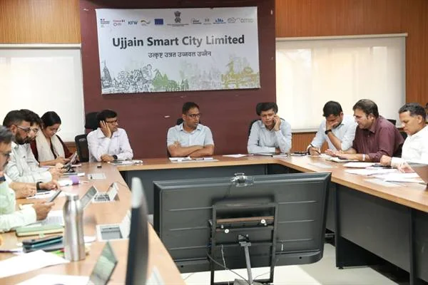 बैठक कक्ष में मेज के दोनों ओर बैठे अधिकारी, सामने मॉनिटर और पीछे उज्जैन स्मार्ट सिटी लिमिटेड का बोर्ड